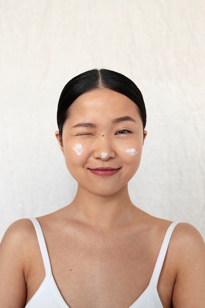 Coup moyen femme coréenne posant avec de la crème pour le visage
