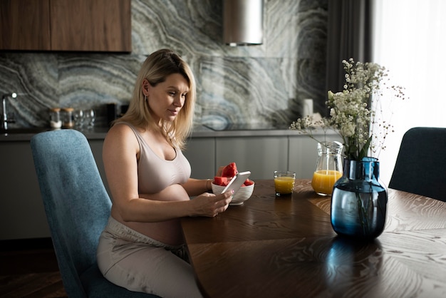 Coup moyen femme enceinte assise à table