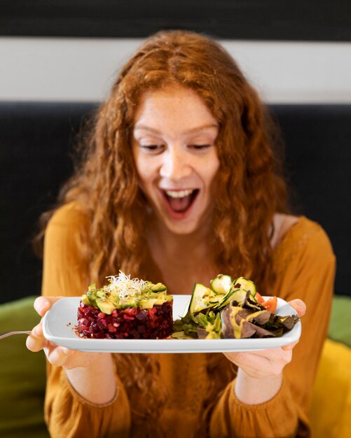 Coup moyen femme excitée avec assiette de nourriture