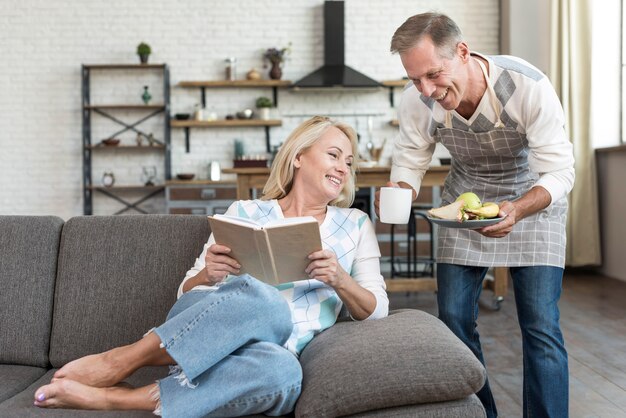 Coup moyen femme heureuse lisant sur le canapé