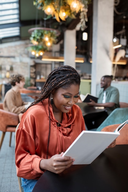 Photo gratuite coup moyen femme lisant dans un café