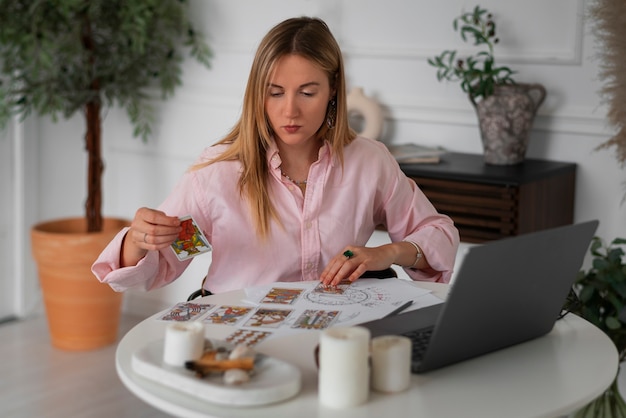 Coup moyen femme lisant le tarot avec un ordinateur portable