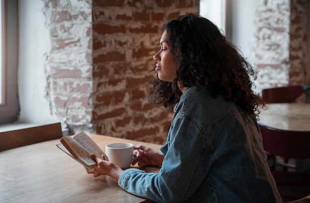 Photo gratuite coup moyen femme avec livre dans un café