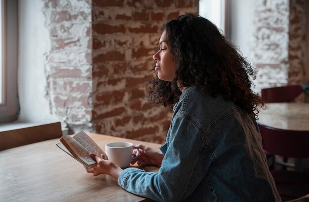 Coup moyen femme avec livre dans un café