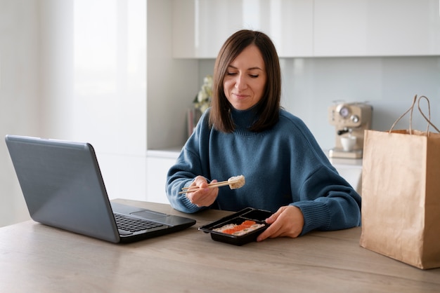 Coup moyen femme mangeant des sushis à la maison