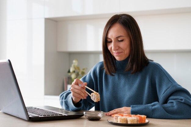 Coup moyen femme mangeant des sushis à la maison