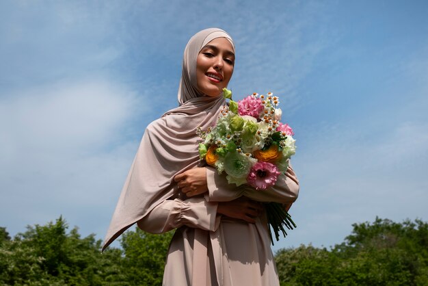 Coup moyen femme musulmane posant avec des fleurs