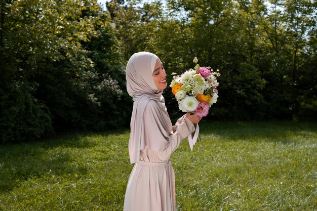 Coup moyen femme musulmane posant avec des fleurs