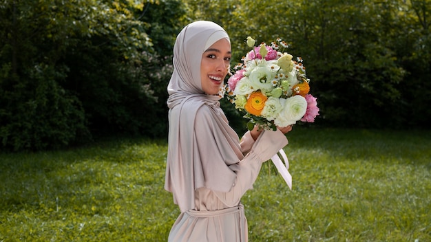 Photo gratuite coup moyen femme musulmane posant avec des fleurs