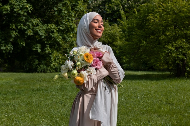 Photo gratuite coup moyen femme musulmane posant avec des fleurs