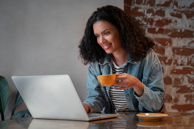 Coup moyen femme avec ordinateur portable dans un café