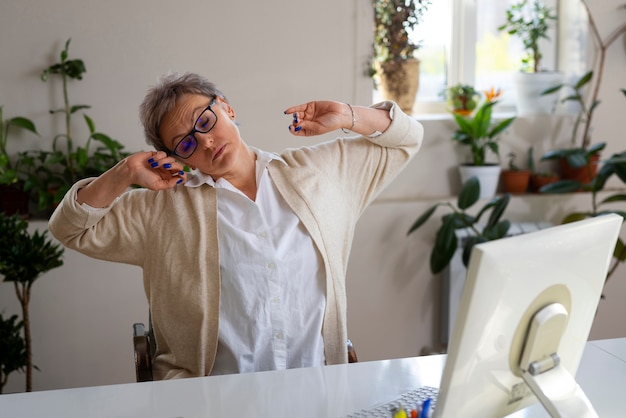 Photo gratuite coup moyen femme qui s'étend au bureau