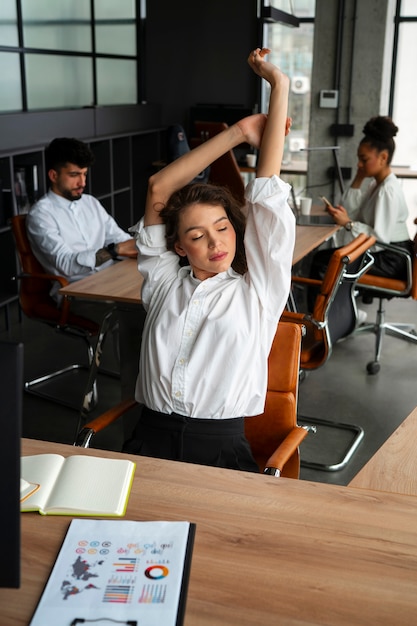 Photo gratuite coup moyen femme qui s'étend au travail