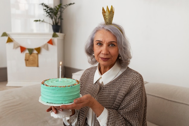 Coup moyen femme senior célébrant avec un gâteau