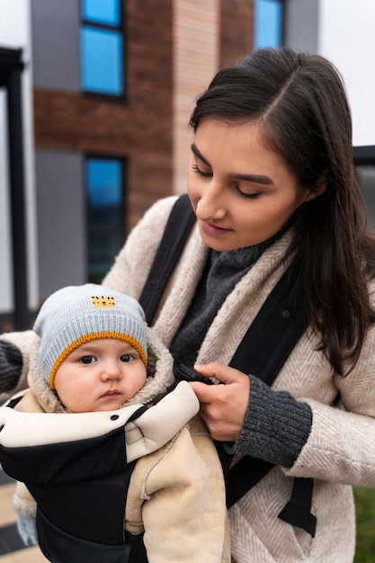 Coup moyen femme tenant bébé dans un porte-bébé