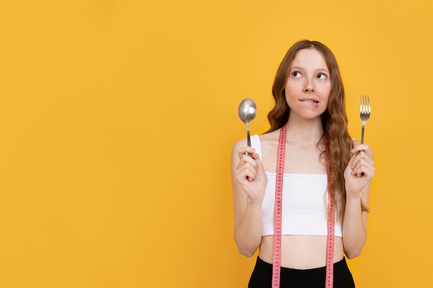 Photo gratuite coup moyen femme tenant une fourchette et une cuillère