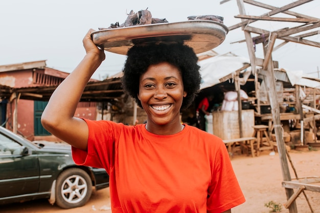 Photo gratuite coup moyen femme transportant de la nourriture sur la tête