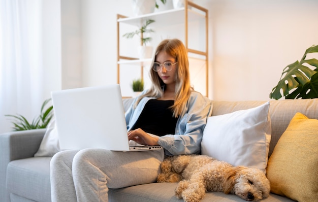 Coup moyen femme travaillant avec chien sur canapé