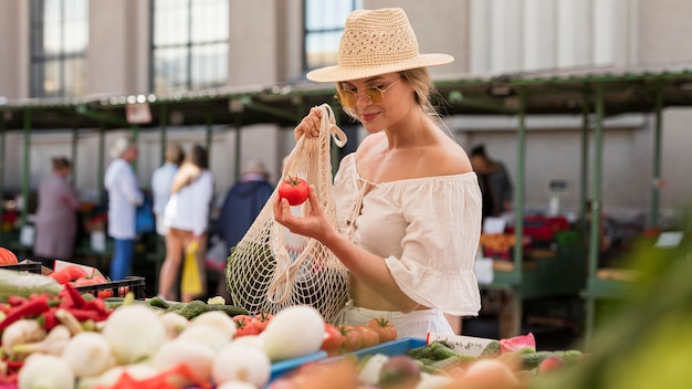 Photo gratuite coup moyen femme utilisant un sac bio pour les légumes