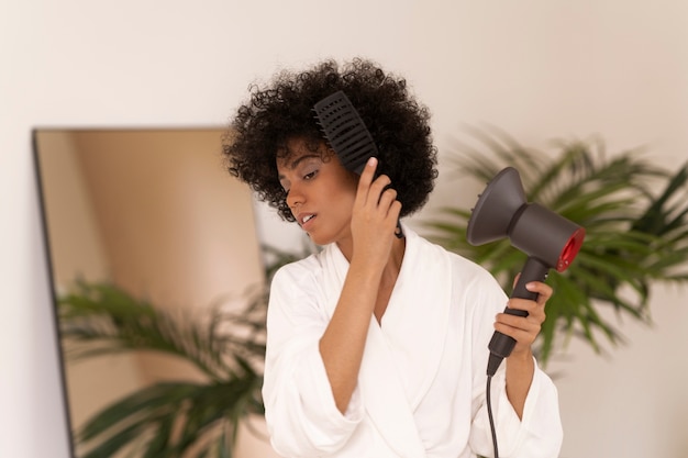 Coup moyen femme utilisant un sèche-cheveux