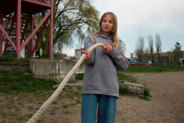 Photo gratuite coup moyen fille jouant au tir à la corde sur la plage