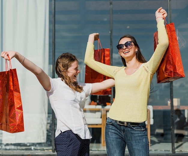 Coup moyen filles heureuse avec des sacs à provisions rouges