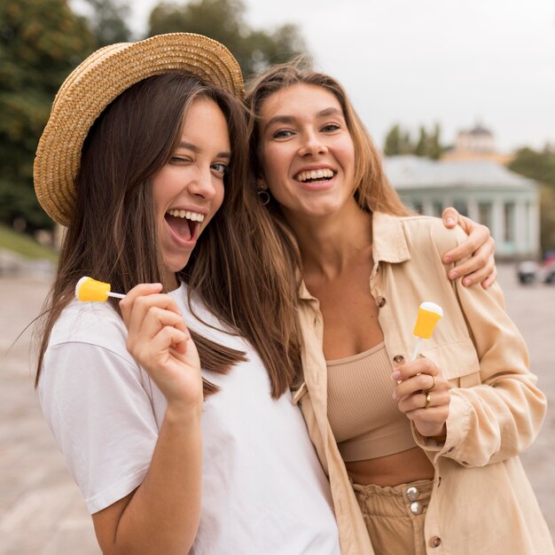 Coup moyen des filles heureuses posant avec des bonbons