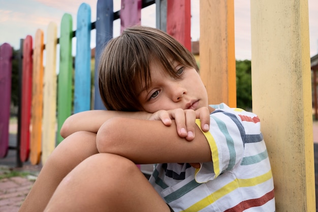 Photo gratuite coup moyen garçon triste dans le parc