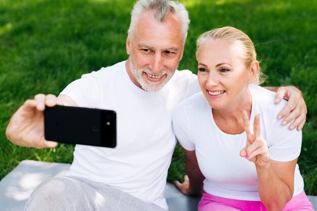 Coup moyen des gens heureux prenant selfies à l'extérieur