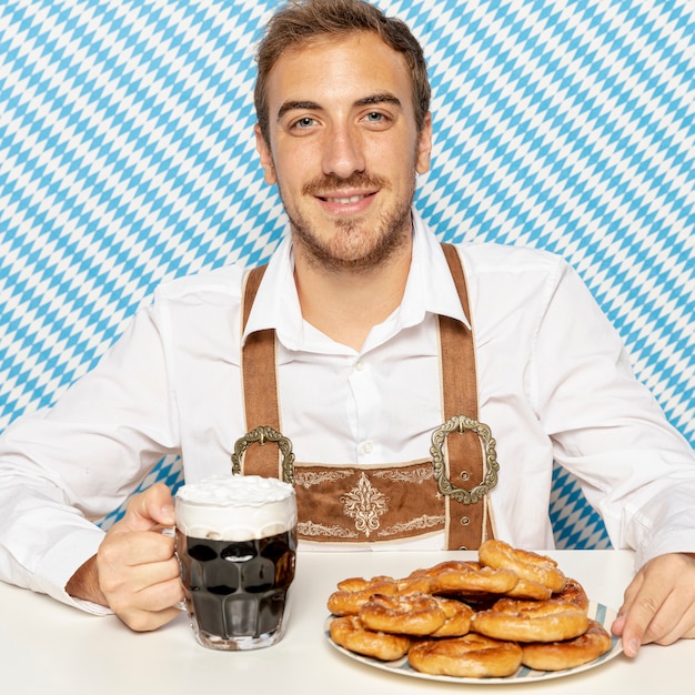 Coup moyen d'homme avec des bretzels et de la bière noire