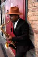 Photo gratuite coup moyen homme avec chapeau jouant du saxophone