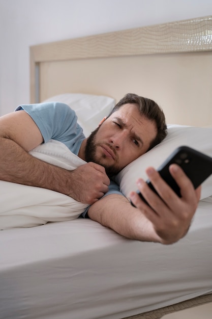Coup moyen homme couché dans son lit avec téléphone