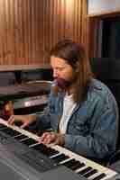 Photo gratuite coup moyen homme jouant du piano en studio