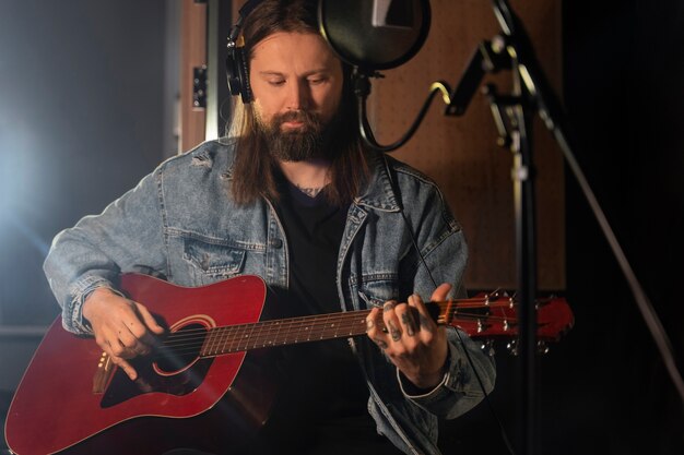 Coup moyen homme jouant de la guitare en studio