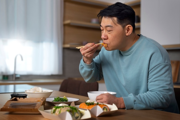Coup moyen homme mangeant de la nourriture asiatique