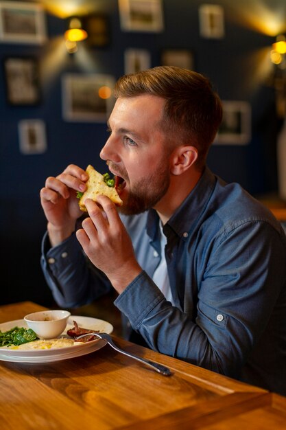 Coup moyen homme mangeant un sandwich