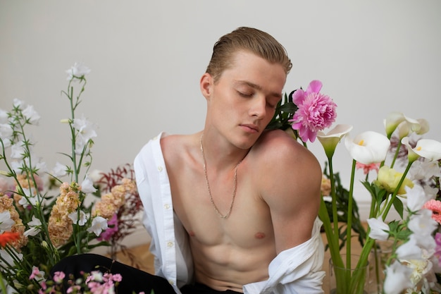 Photo gratuite coup moyen homme posant avec des fleurs