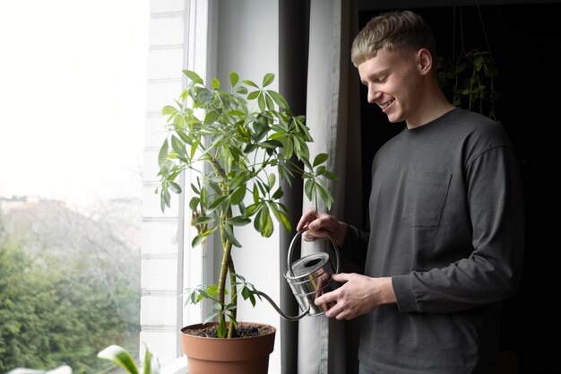 Coup moyen homme souriant arrosant une plante