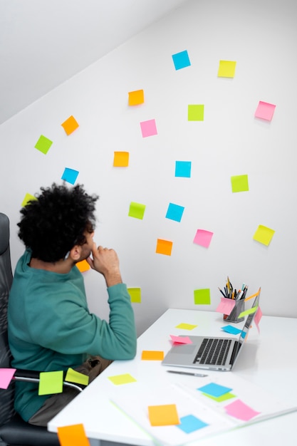 Coup moyen homme travaillant avec post son au bureau