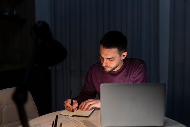 Coup moyen homme travaillant tard dans la nuit sur ordinateur portable