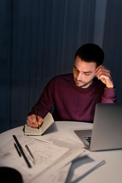 Coup moyen homme travaillant tard dans la nuit sur ordinateur portable