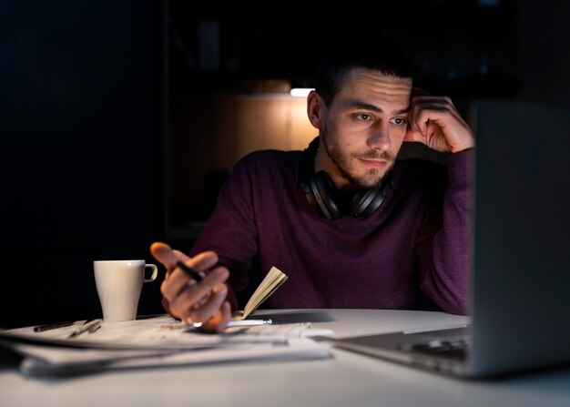 Coup moyen homme travaillant tard dans la nuit sur ordinateur portable