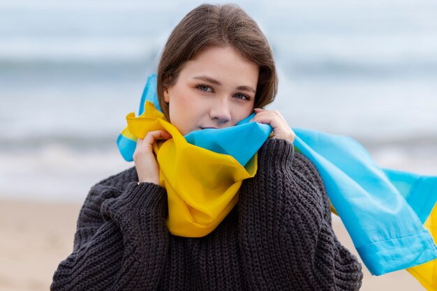 Coup moyen jeune femme portant le drapeau ukrainien à la plage