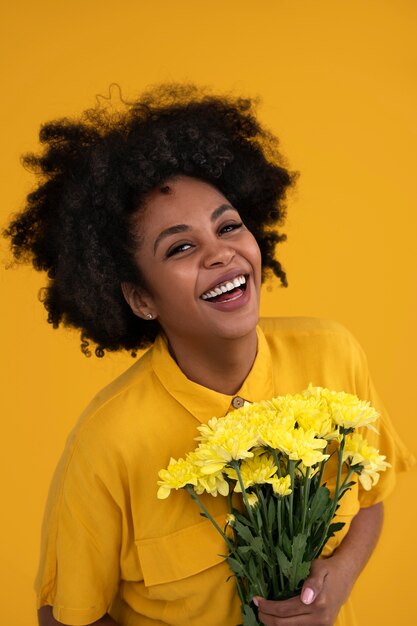 Photo gratuite coup moyen jeune femme posant avec des fleurs