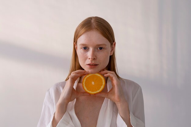 Coup moyen jeune femme tenant une tranche d'orange