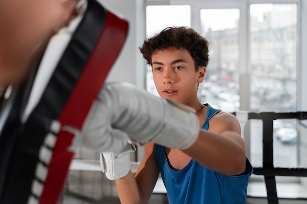 Photo gratuite coup moyen jeune garçon boxe