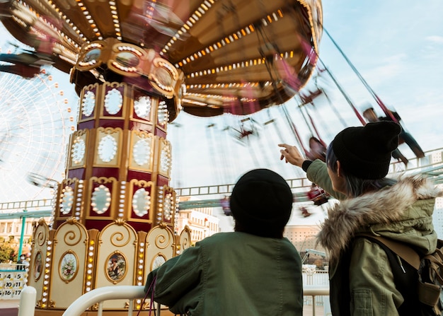 Photo gratuite coup moyen joli couple pointant sur le carrousel