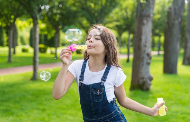 Coup moyen jolie petite fille faisant des bulles de savon