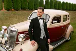 Photo gratuite coup moyen marié posant avec une voiture vintage