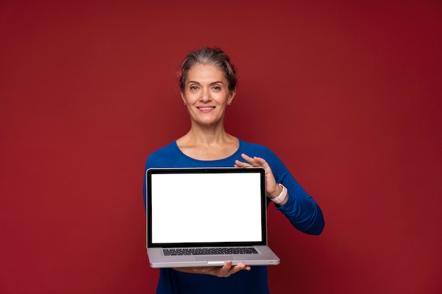 Coup moyen senior woman holding laptop